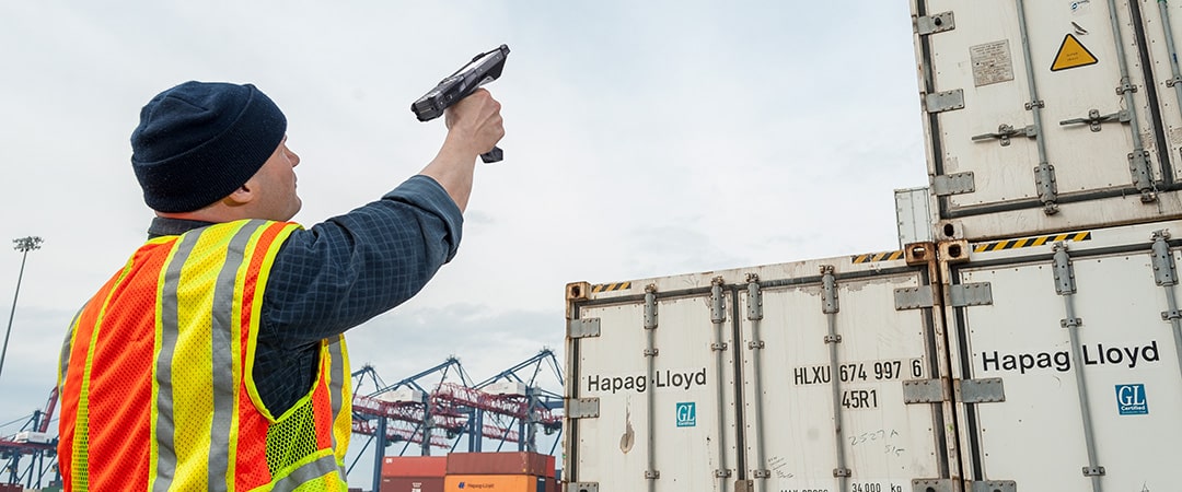 Man pointing handheld RFID scanner at containers