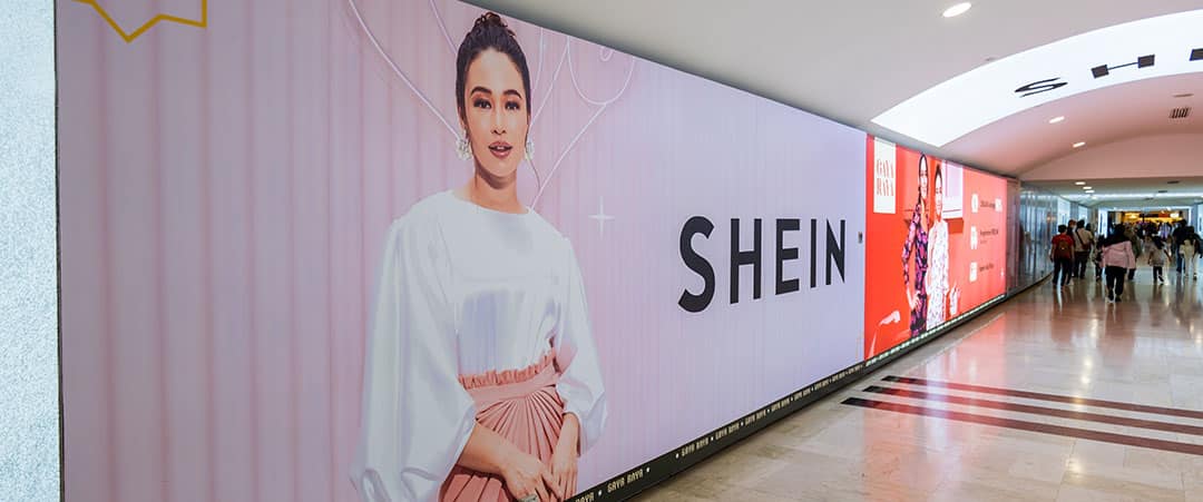 A large Shein advertising display on a subway wall.